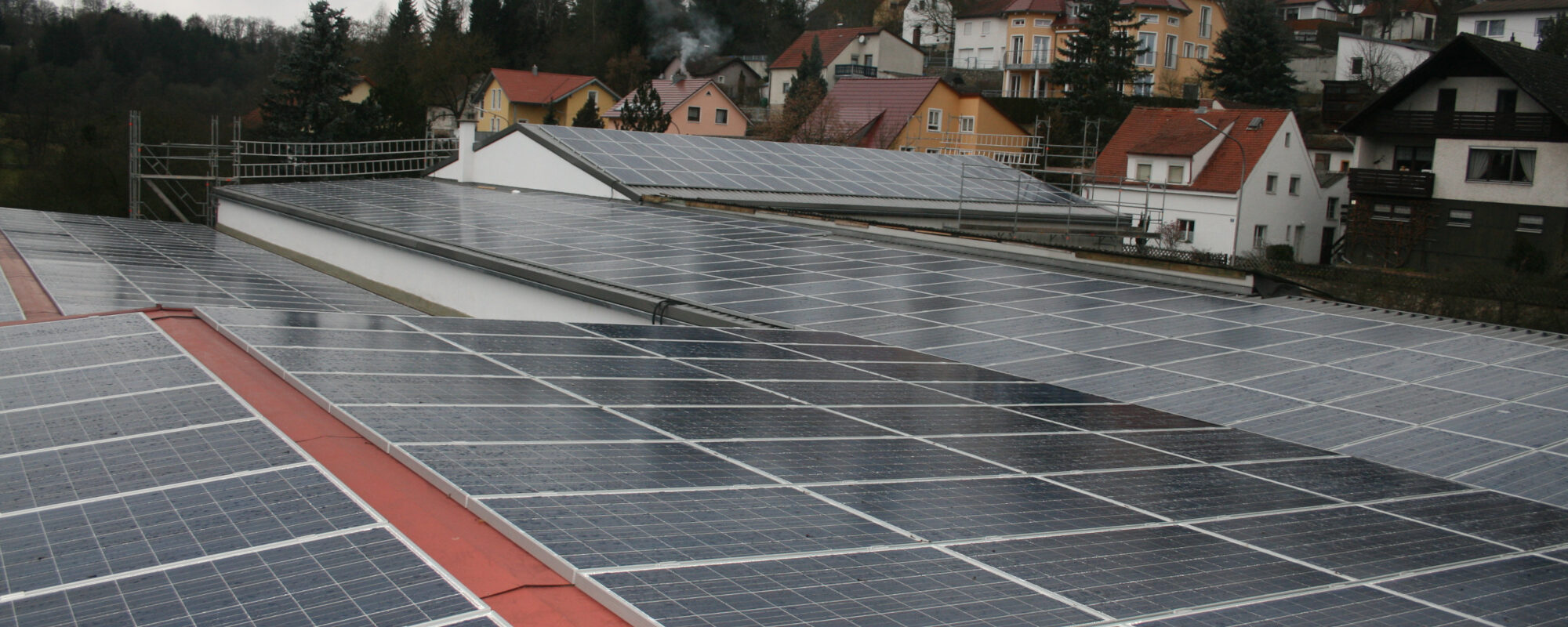 Ein Blick über die Große Solar Anlage der Firma. Im Hintergrund Häuser und Bäume.