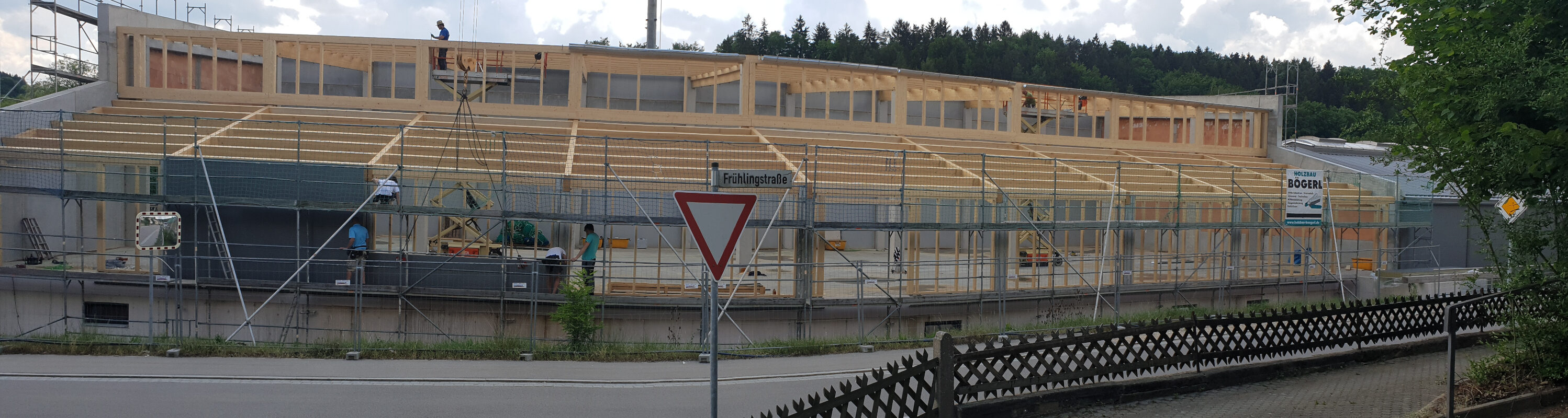 Ein Bild der Lagerhalle. Die Lagerhalle wird gerade gebaut Bauarbeiter stehen auf und unter Dem Hölzernen Umriss der Halle.